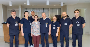 A group of medical professionals standing together in a modern clinic with a patient.