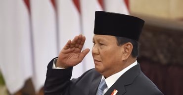 Indonesian President Prabowo Subianto saluting in front of Indonesian flags.