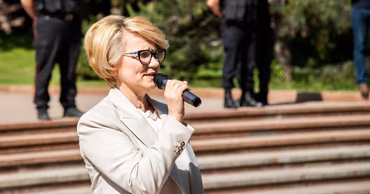 Alla Darovannaya speaking into a microphone outdoors.