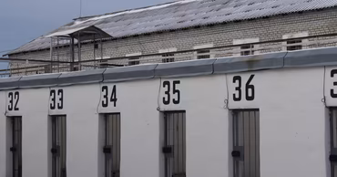 Exterior view of a prison building with numbered cell doors.