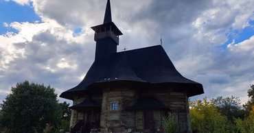 A traditional wooden church in Moldova under a cloudy sky.