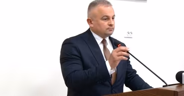 Alexandru Machidon speaking at a podium during an official event.