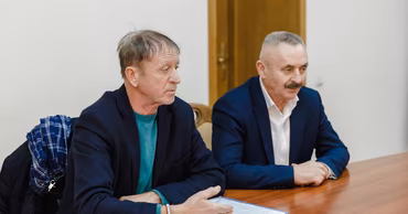 Vasile Bumacov sitting at a table during a meeting or press conference.