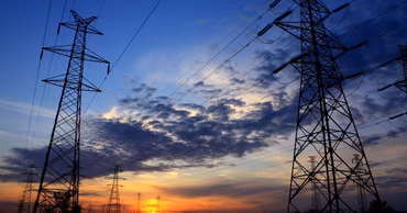 High-voltage electricity transmission towers against a sunset sky.