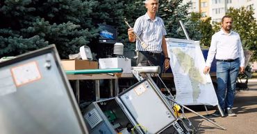 Specialists from the Moldovan Hydrometeorological Service demonstrating monitoring equipment and a map of the country.