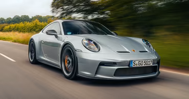 A silver Porsche 911 GT3 driving on a road with motion blur.
