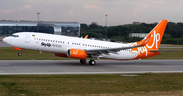 A SkyUp Airlines passenger plane taking off from an airport runway.