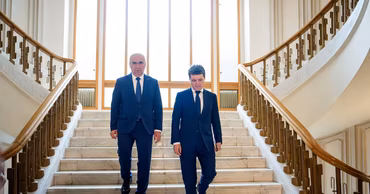 Ilie Bolojan and Alexandru Munteanu walking down a staircase in a formal building.