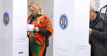 People voting in a Moldovan election at booths with the Central Electoral Commission logo.