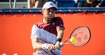 Radu Albot hitting a tennis ball during a match.
