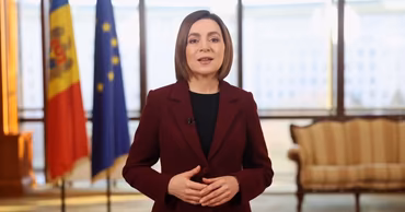 Maia Sandu speaking in front of Moldovan and European Union flags.