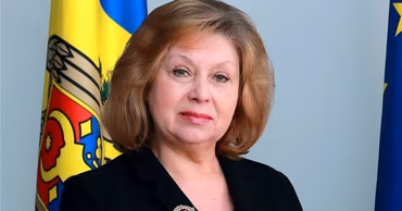 Portrait of Moldovan diplomat Larisa Miculet in front of the Moldovan flag.
