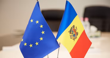Small flags of the European Union and Moldova placed on a table.