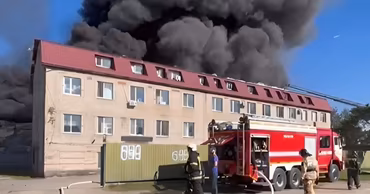 Firefighters at the scene of a large warehouse fire in Chisinau with thick black smoke.