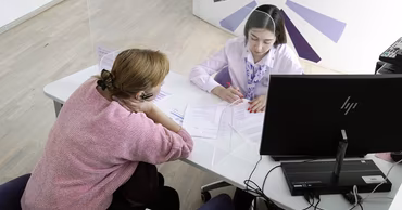 A woman consulting with an employment agency officer at a desk in an office.