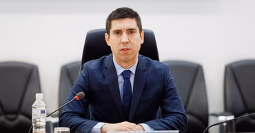Mihai Popșoi sitting at a conference table with a nameplate in front of him.