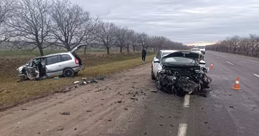 Two heavily damaged cars on the side of a road after a traffic accident.