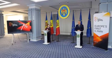 Eugen Osmokescu speaking at a podium during a business conference in Chisinau.