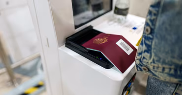 A person scanning a passport at an automated border control kiosk.