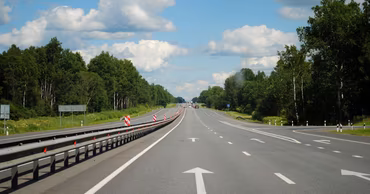 A view of a modern asphalt highway with road markings and guardrails.