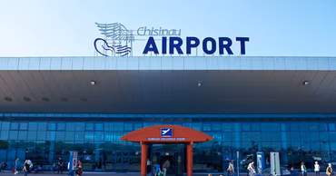 Exterior view of the Chisinau International Airport terminal building with people walking in front.