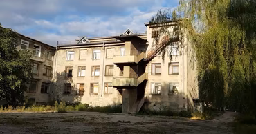 An old multi-story school building in Balti with an external staircase.