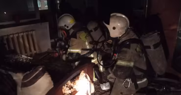 Moldovan firefighters in protective gear working inside a dark, damaged apartment.