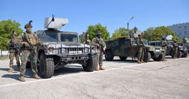 Moldovan soldiers standing in formation next to military Humvee vehicles on a paved ground.