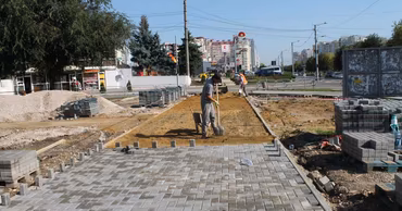 Construction workers laying paving stones on a sidewalk in Chisinau during road renovation works.