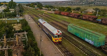 An aerial view of a Moldovan passenger train at a railway station with freight cars nearby.