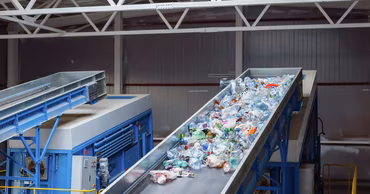 Plastic bottles on a conveyor belt at a waste recycling facility.