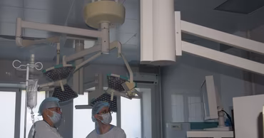 Medical staff in a hospital operating room using specialized equipment.