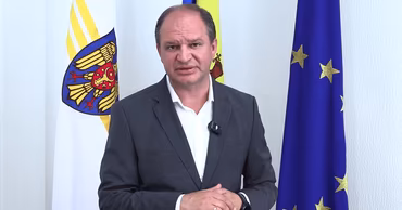 Ion Ceban, Mayor of Chisinau, standing in front of Moldovan and European Union flags.