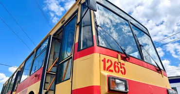 A low-angle shot of a red and yellow Chisinau trolleybus against a blue sky.