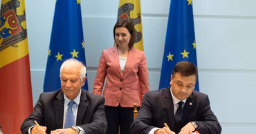 Josep Borrell and Dorin Recean signing documents with Maia Sandu standing in the background.