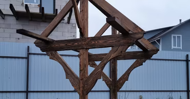 A wooden structure over a concrete water well in a residential backyard.