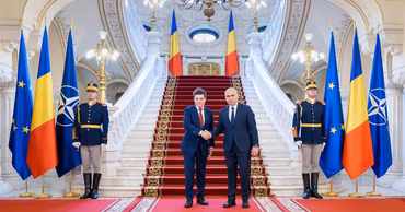 Ilie Bolojan shaking hands with an official in a formal government building.