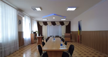 An empty meeting room in a Moldovan local administration office with a Moldovan flag.