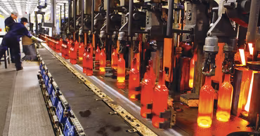 Automated production line manufacturing glass bottles in a factory setting.