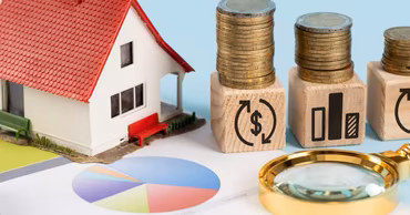 A miniature house, stacks of coins on wooden blocks, and a magnifying glass on charts.