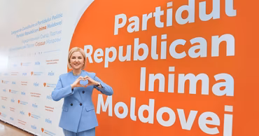 Irina Vlah posing in front of a Partidul Republican Inima Moldovei banner.