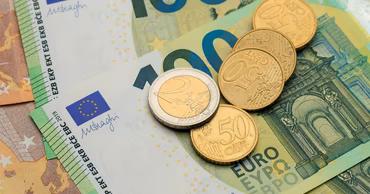 Euro banknotes and coins arranged on a flat surface.