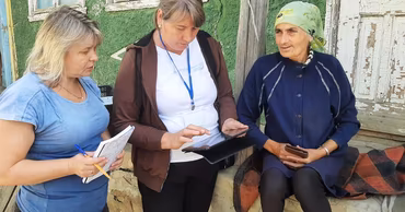 Two women from the National Bureau of Statistics interviewing a rural resident for a survey.