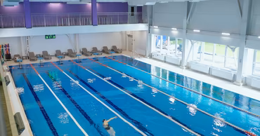 A high-angle view of the renovated indoor swimming pool at USM with a swimmer.