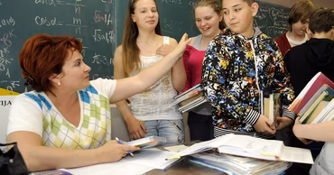 A teacher interacting with students in a classroom setting.