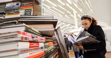 A woman browsing books at a bookstore or library in Moldova.