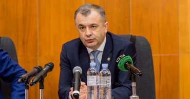 Ion Chicu sitting at a table with microphones during a press conference.