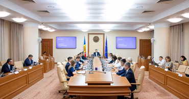 Moldovan government officials attending a cabinet meeting in a conference room.