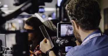 A cameraman filming a person on a professional set.