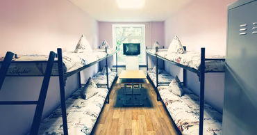 A dormitory room with bunk beds and a small table.